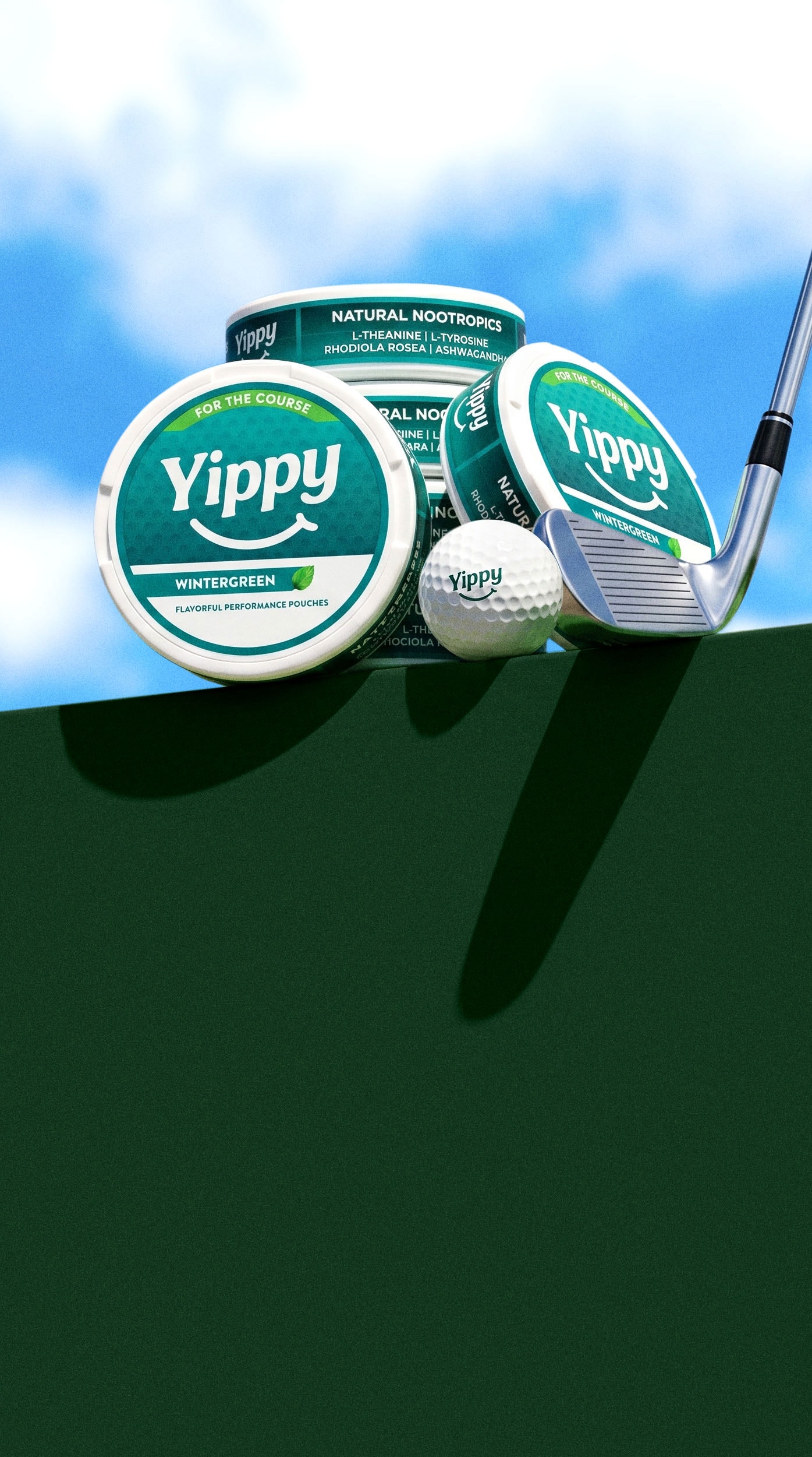 Still life of Yippy For The Course Wintergreen tins on a green putting surface with a golf ball and putter under a blue sky with drifting clouds